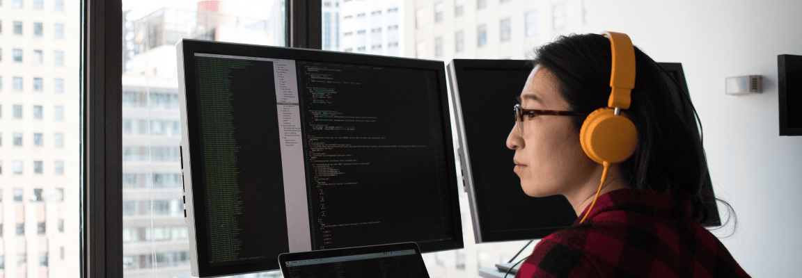 Female programmer sits in front of screens