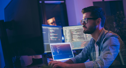 Man at desk with several computer monitors