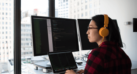 Female programmer sits in front of screens