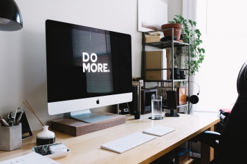 Computer screen on a desk with the words 'DO MORE' in large white letters on a black background